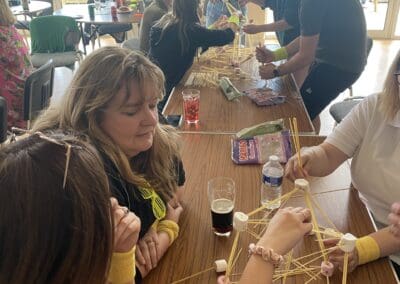 Bren watches on as her team complete the marshmallow and straw challenge